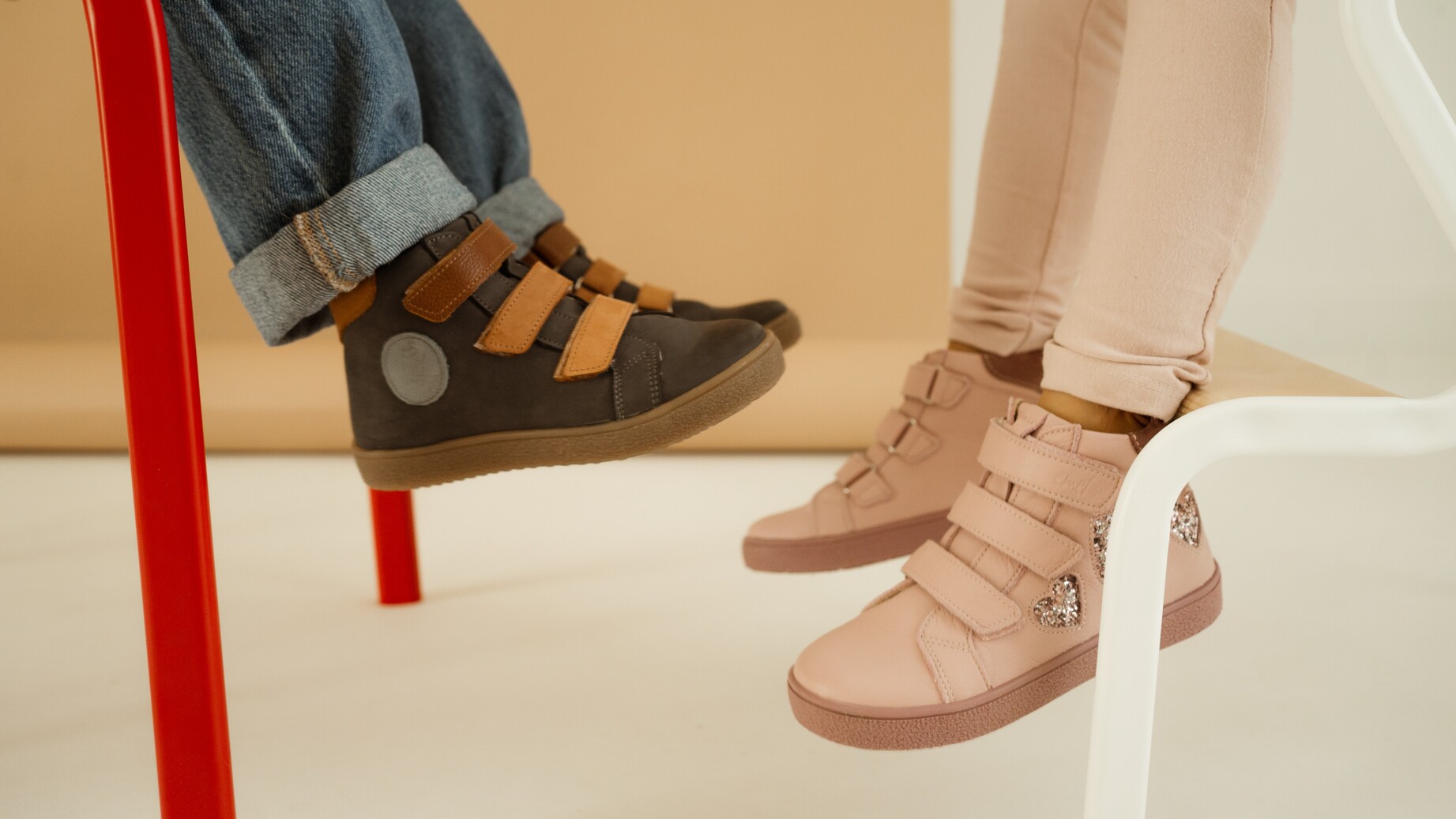 Zbliżenie na buty dzieci – dziewczynka w różowych, a chłopiec w granatowych wysokich trampkach Emel z naturalnej skóry, idealnych na jesień.