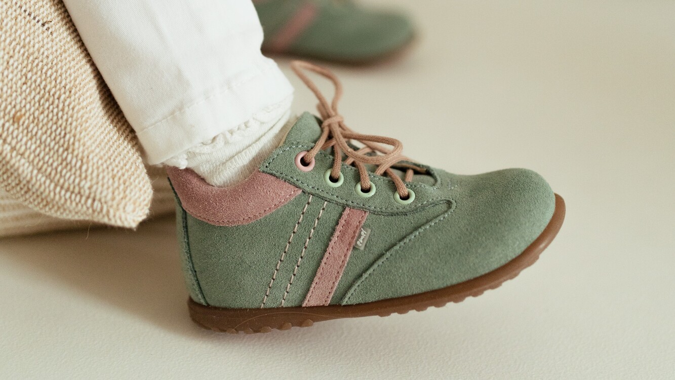 Zbliżenie na miętowe trzewiki dziecięce z naturalnej skóry welurowej z serii Roczki marki Emel na stópkach dziecka.