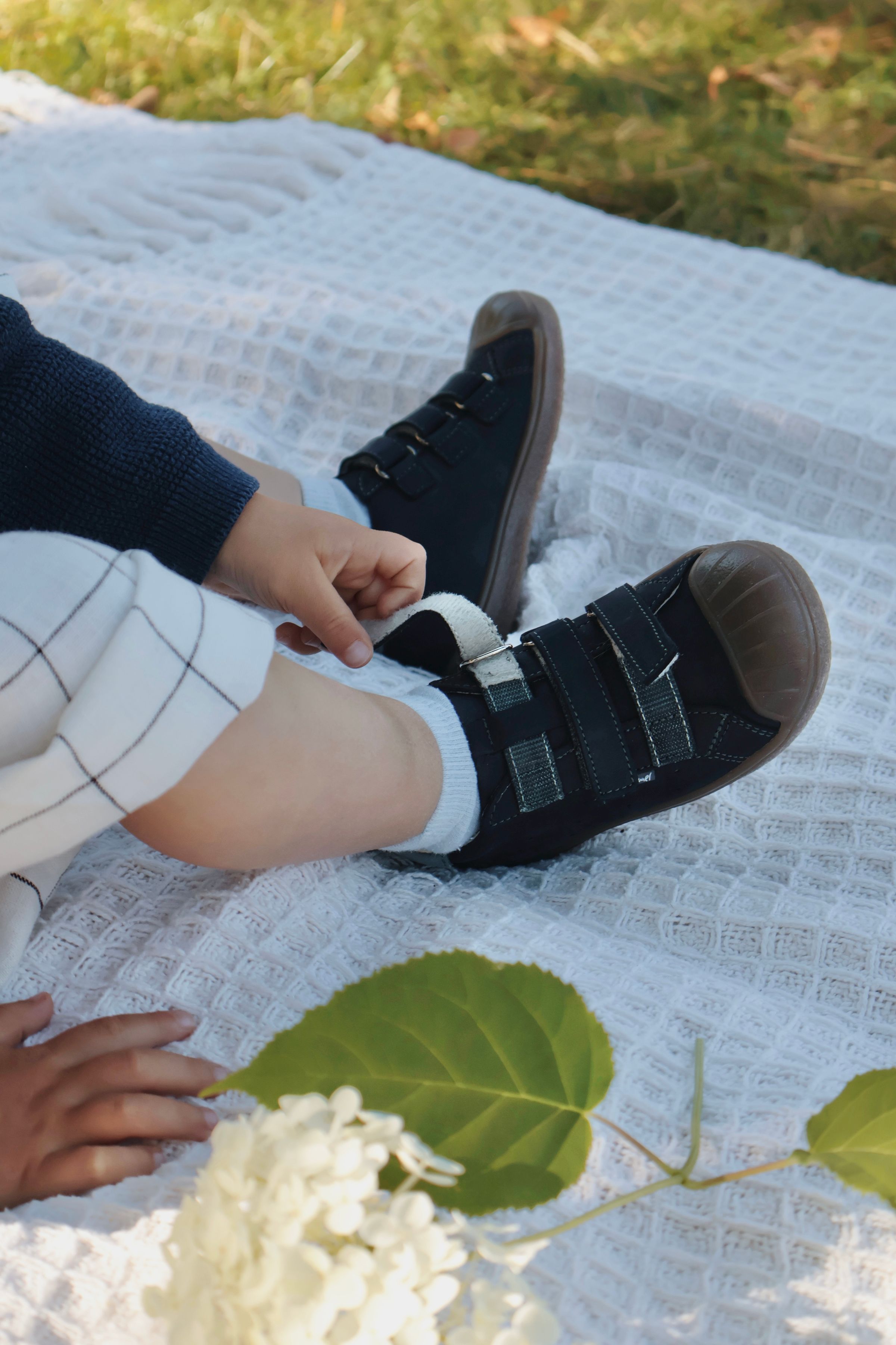 Buciki Emel Berlin założone na dziecko siedzące na białym kocyku