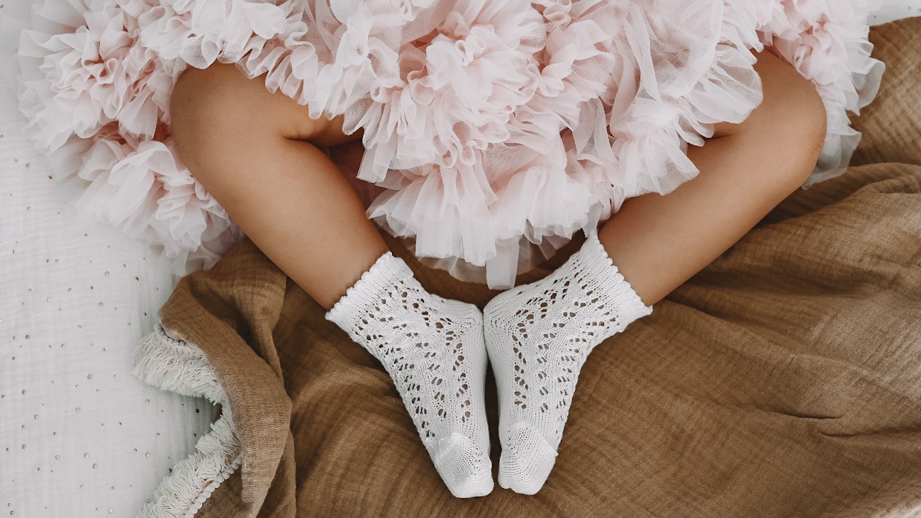 Dziewczynka w białych ażurowych skarpetkach i tiulowej spódnicy.