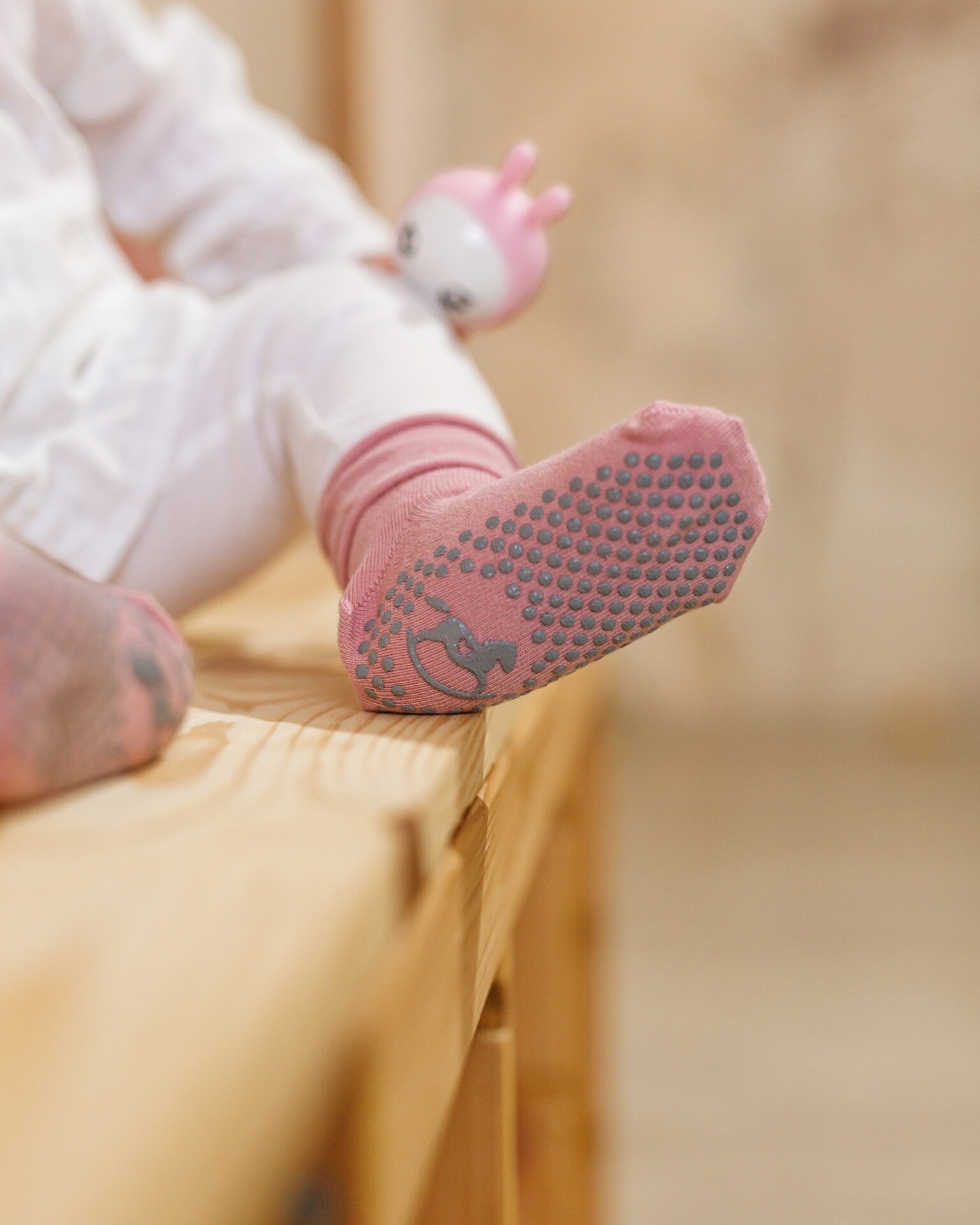 Różowe skarpetki antypoślizgowe dla dzieci marki Emel – zbliżenie na stopę dziewczynki, wygodne i bezpieczne.