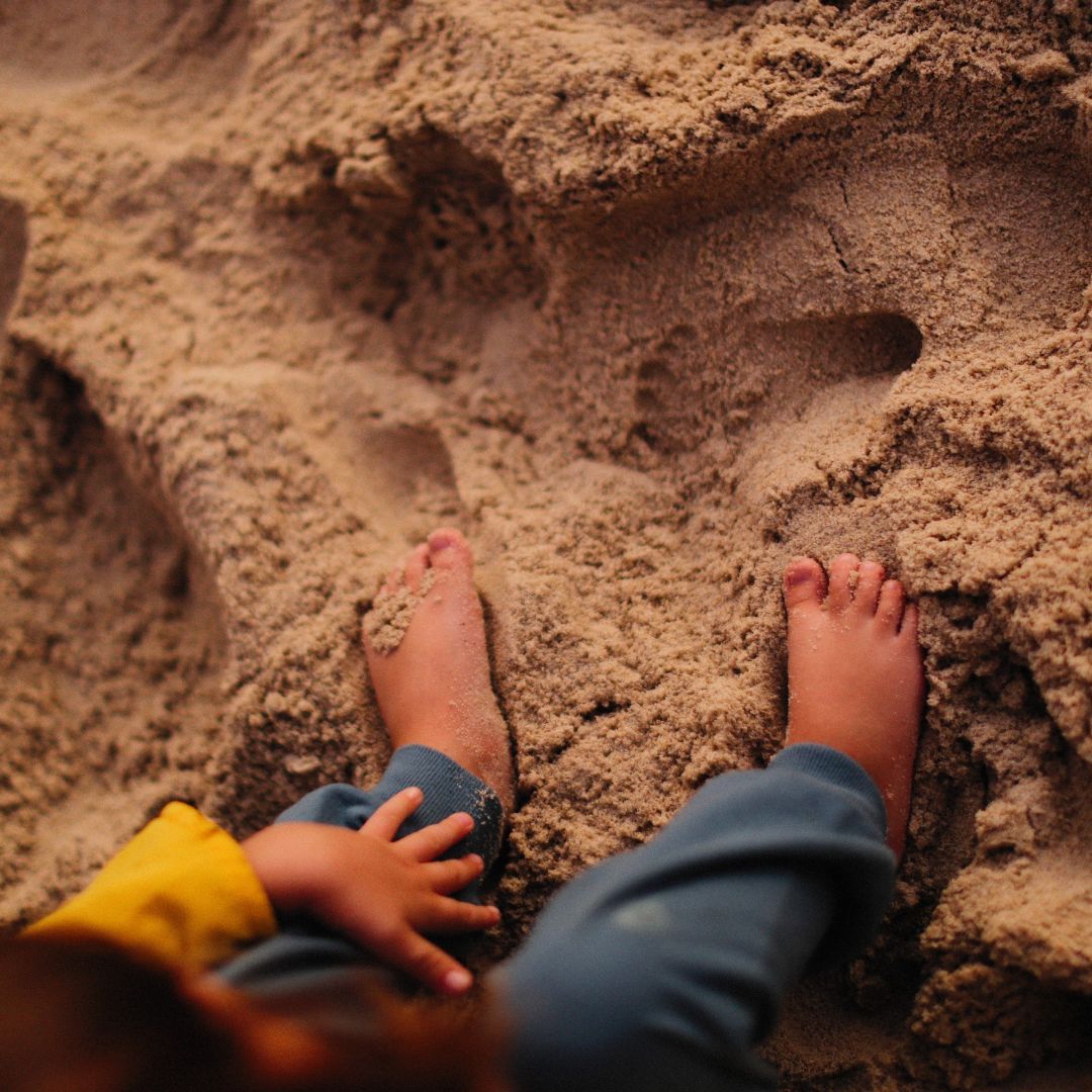 Dziecko stoi bosymi stopkami na piasku